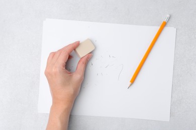 Photo of Woman with graphite pencil, eraser and paper sheet at light table, top view