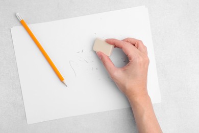 Photo of Woman with graphite pencil, eraser and paper sheet at light table, top view