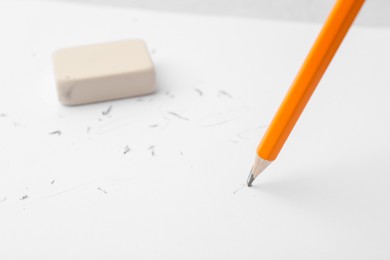 Photo of Graphite pencil and eraser on paper sheet, closeup