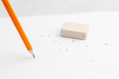 Photo of Graphite pencil and eraser on paper sheet, closeup