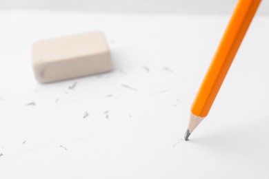 Photo of Graphite pencil and eraser on paper sheet, closeup