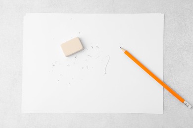 Photo of Graphite pencil, eraser and paper sheet on light table, top view