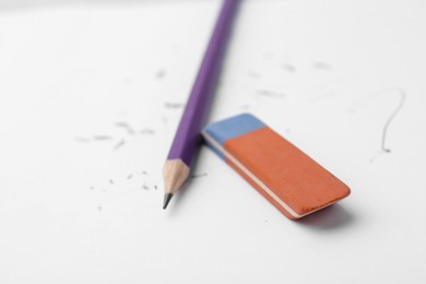 Photo of Graphite pencil and eraser on paper sheet, closeup
