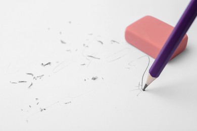 Photo of Graphite pencil and eraser on paper sheet, closeup