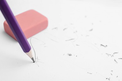 Photo of Graphite pencil and eraser on paper sheet, closeup