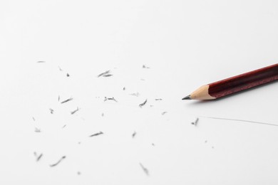 Photo of Graphite pencil and eraser shavings on paper sheet, closeup