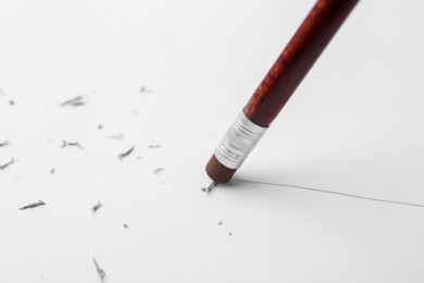 Photo of Graphite pencil with eraser on paper sheet, closeup