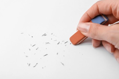 Photo of Woman erasing pencil strokes from paper sheet, closeup