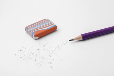Photo of Graphite pencil and eraser on paper sheet, closeup