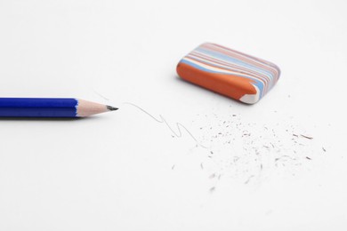 Photo of Graphite pencil and eraser on paper sheet, closeup