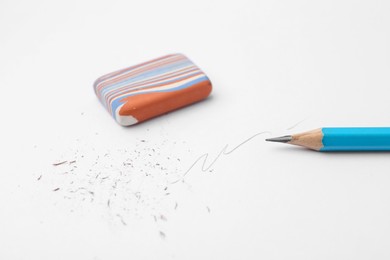 Photo of Graphite pencil and eraser on paper sheet, closeup