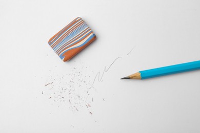 Photo of Graphite pencil and eraser on paper sheet, top view
