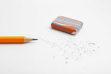 Photo of Graphite pencil and eraser on paper sheet, closeup