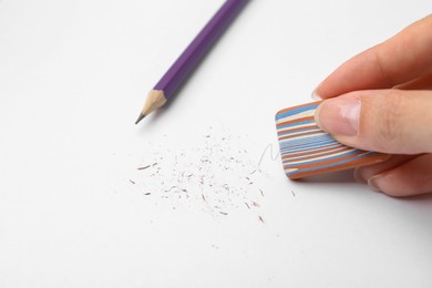 Photo of Woman erasing pencil strokes from paper sheet, closeup