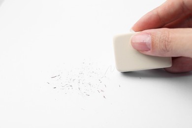 Photo of Woman erasing pencil strokes from paper sheet, closeup