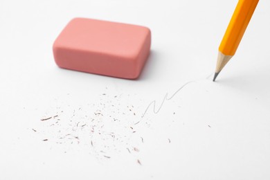 Photo of Graphite pencil and eraser on paper sheet, closeup