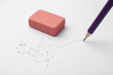 Photo of Graphite pencil and eraser on paper sheet, closeup