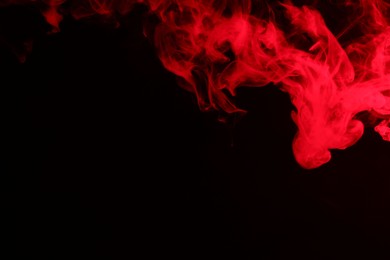 Photo of Hookah smoke in red light on black background, closeup. Space for text