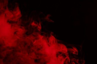 Photo of Hookah smoke in red light on black background, closeup. Space for text
