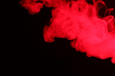 Photo of Hookah smoke in red light on black background, closeup. Space for text