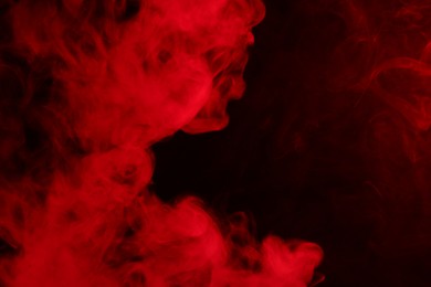 Photo of Hookah smoke in red light on black background, closeup. Space for text