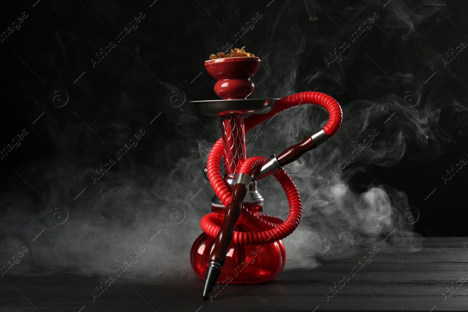 Hookah on wooden table with smoke against black background Photo of Hookah on wooden table with smoke against black background