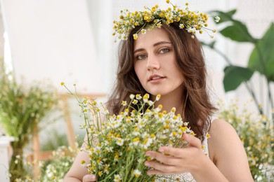 Photo of Portrait of beautiful woman with chamomile flowers indoors