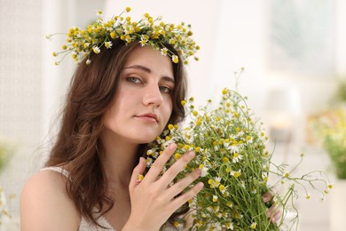 Photo of Portrait of beautiful woman with chamomile flowers indoors