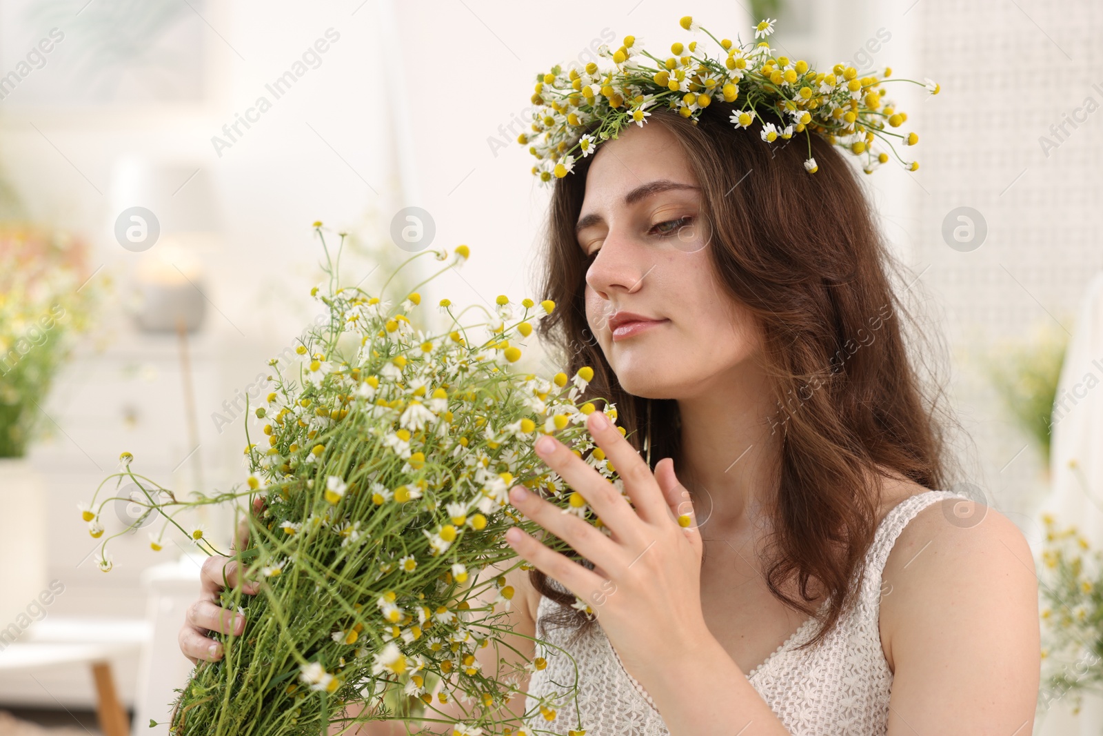 Portrait of beautiful woman with chamomile flowers indoors Photo of Portrait of beautiful woman with chamomile flowers indoors