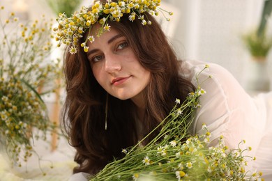 Photo of Portrait of beautiful woman with chamomile flowers indoors