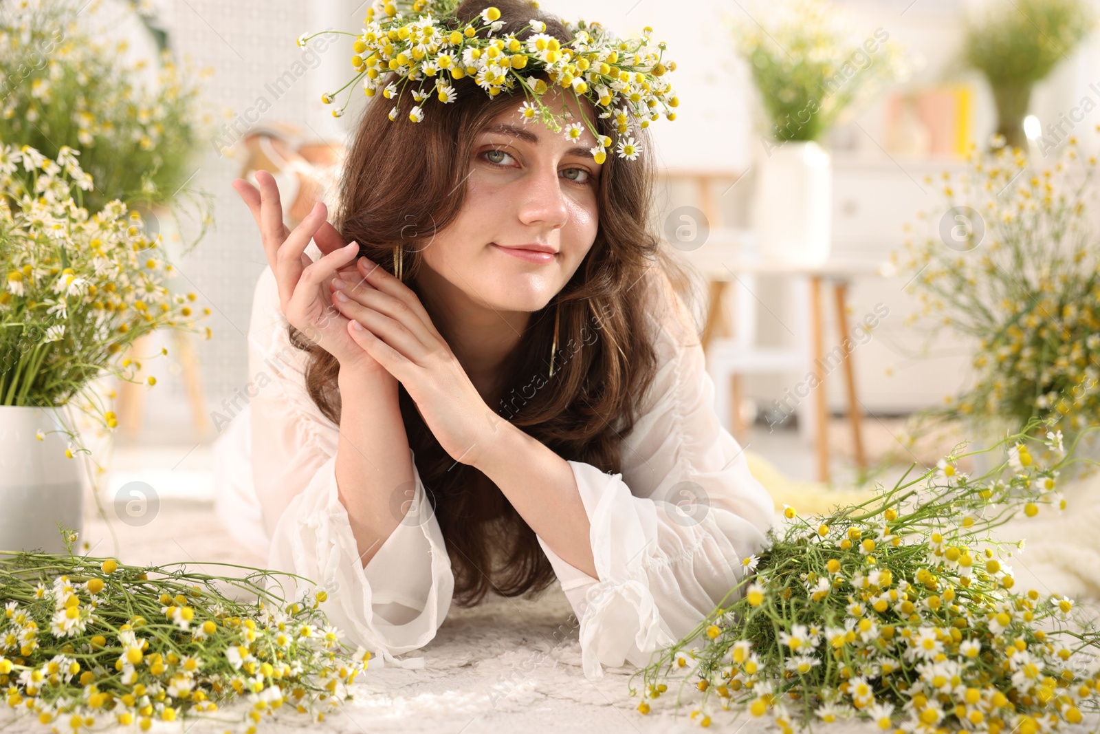 Beautiful woman with chamomile flowers on floor indoors Photo of Beautiful woman with chamomile flowers on floor indoors