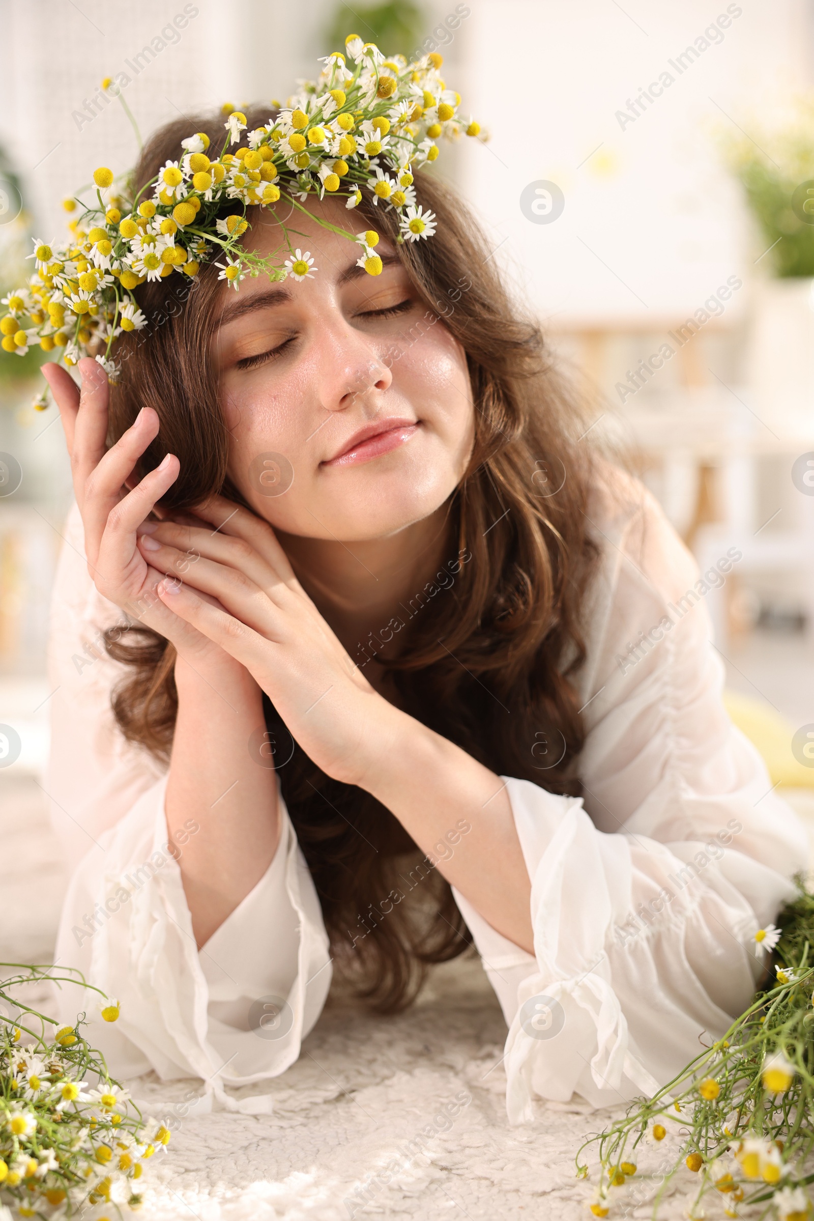 Beautiful woman with chamomile flowers on floor indoors Photo of Beautiful woman with chamomile flowers on floor indoors