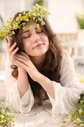 Photo of Beautiful woman with chamomile flowers on floor indoors
