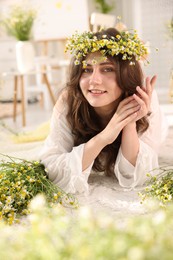Photo of Beautiful woman with chamomile flowers on floor indoors
