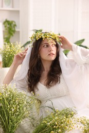 Photo of Portrait of beautiful woman with chamomile flowers indoors