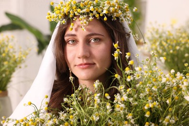 Photo of Portrait of beautiful woman with chamomile flowers indoors