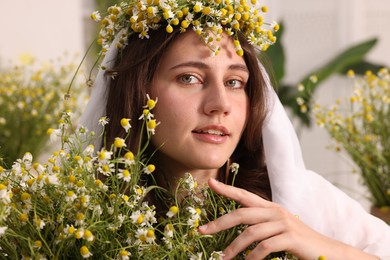 Photo of Portrait of beautiful woman with chamomile flowers indoors