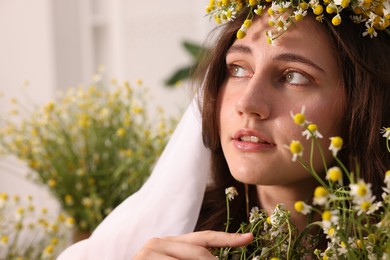 Photo of Portrait of beautiful woman with chamomile flowers indoors
