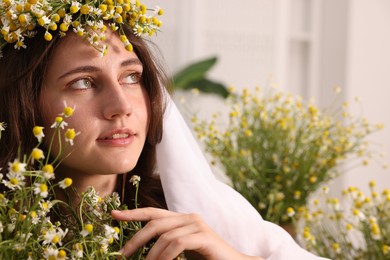 Photo of Portrait of beautiful woman with chamomile flowers indoors