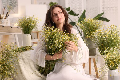 Photo of Portrait of beautiful woman with chamomile flowers indoors