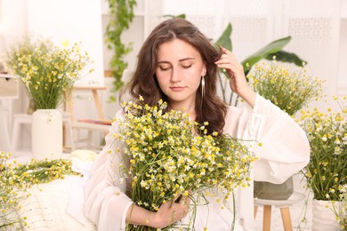 Photo of Portrait of beautiful woman with chamomile flowers indoors