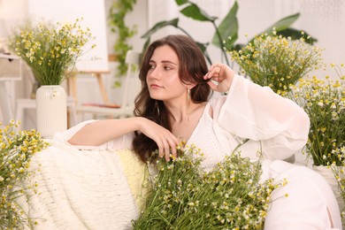 Photo of Portrait of beautiful woman with chamomile flowers indoors