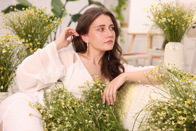 Photo of Portrait of beautiful woman with chamomile flowers indoors