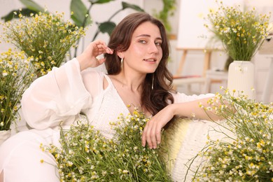 Photo of Portrait of beautiful woman with chamomile flowers indoors