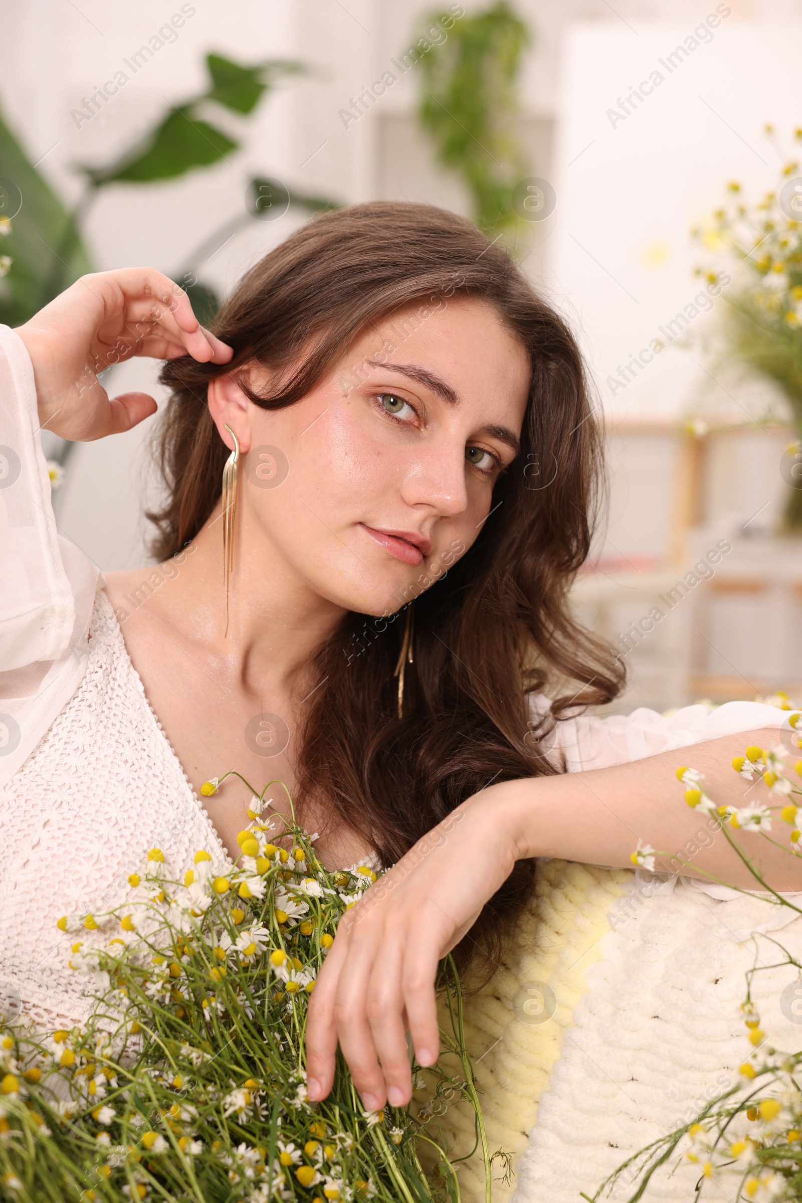 Portrait of beautiful woman with chamomile flowers indoors Photo of Portrait of beautiful woman with chamomile flowers indoors