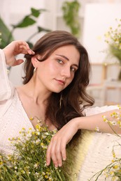 Photo of Portrait of beautiful woman with chamomile flowers indoors
