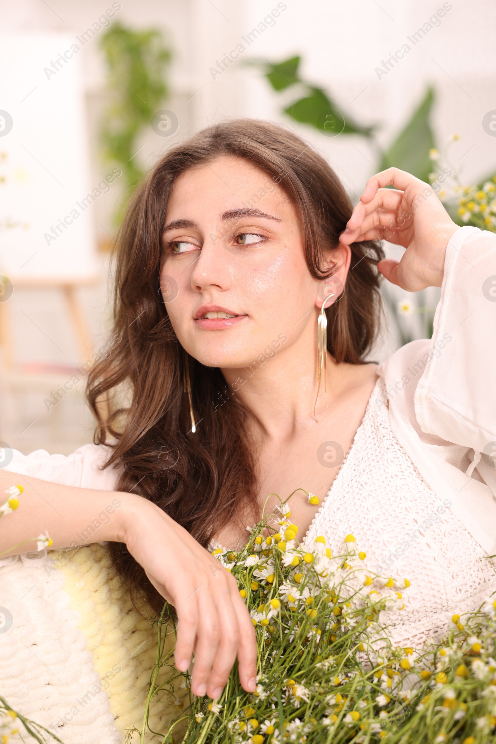 Portrait of beautiful woman with chamomile flowers indoors Photo of Portrait of beautiful woman with chamomile flowers indoors