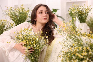 Photo of Portrait of beautiful woman with chamomile flowers indoors