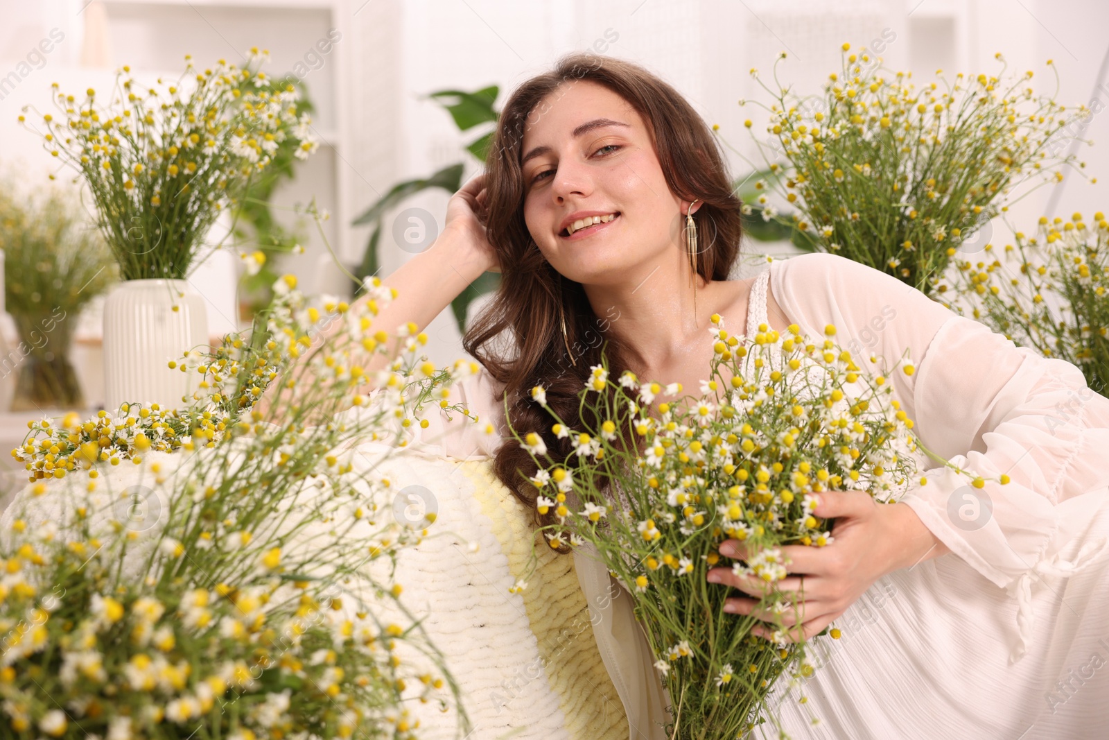 Portrait of beautiful woman with chamomile flowers indoors Photo of Portrait of beautiful woman with chamomile flowers indoors
