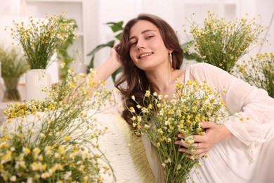 Photo of Portrait of beautiful woman with chamomile flowers indoors